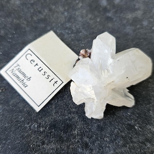 Könnte beinhalten: Ein weißer Cerussit-Kristall-Cluster aus Tsumeb, Namibia. Der Kristall ist durchscheinend und hat eine scharfe, geometrische Form.