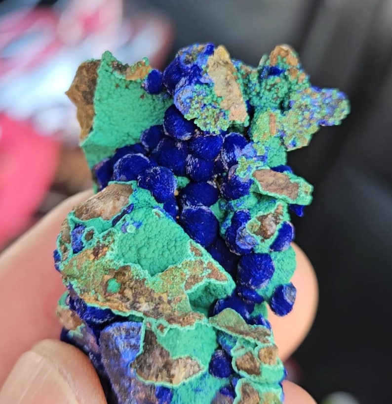 Op de afbeelding: Een close-up van een mineraal specimen met een levendige kleurencombinatie. Het stuk toont een diepblauwe tint, aangevuld met vlekken heldergroen en bruine gebieden. Het oppervlak van het mineraal heeft een textuur.