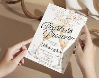 May include: A white invitation card with a watercolor illustration of two champagne flutes filled with bubbly liquid and pearls. The text "Pearls & Prosecco" is written in black cursive font. The invitation is for a bridal shower honoring Nicole White on Saturday, March 9, 2019.