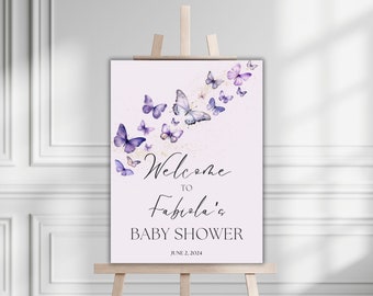 May include: Welcome to Fabiola's Baby Shower sign featuring purple butterflies and gold glitter on a pink background. The date June 2, 2024 is printed at the bottom.