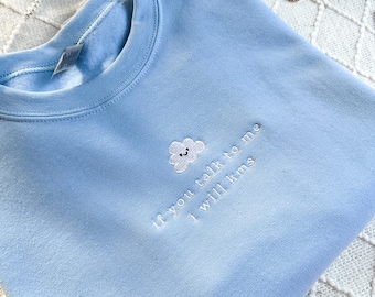 Op de afbeelding: Een lichtblauw sweatshirt met een witte geborduurde wolk en de tekst "If you talk to me I will kms".