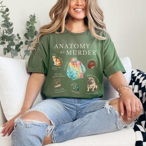May include: A green t-shirt with the text "Anatomy of a Murder" and illustrations of a cat, a tie-dye hoodie, headphones, and a dog. The illustrations are surrounded by text.