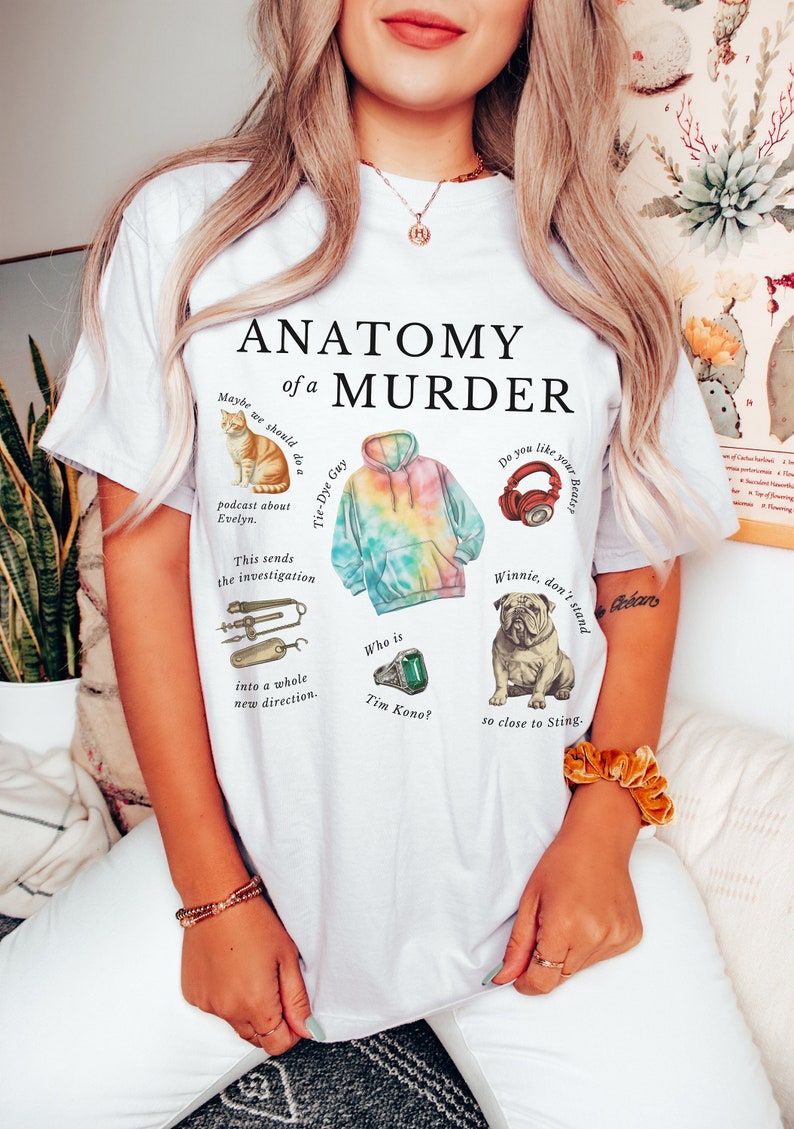 May include: White t-shirt featuring the text "Anatomy of a Murder" and various illustrations, including a cat, a tie-dye hoodie, headphones, a bulldog, and a ring. The text "Maybe we should do a Tie-Dye Guy podcast about Evelyn. This sends the investigation into a whole new direction. Who is Tim Kono?" is also on the shirt.