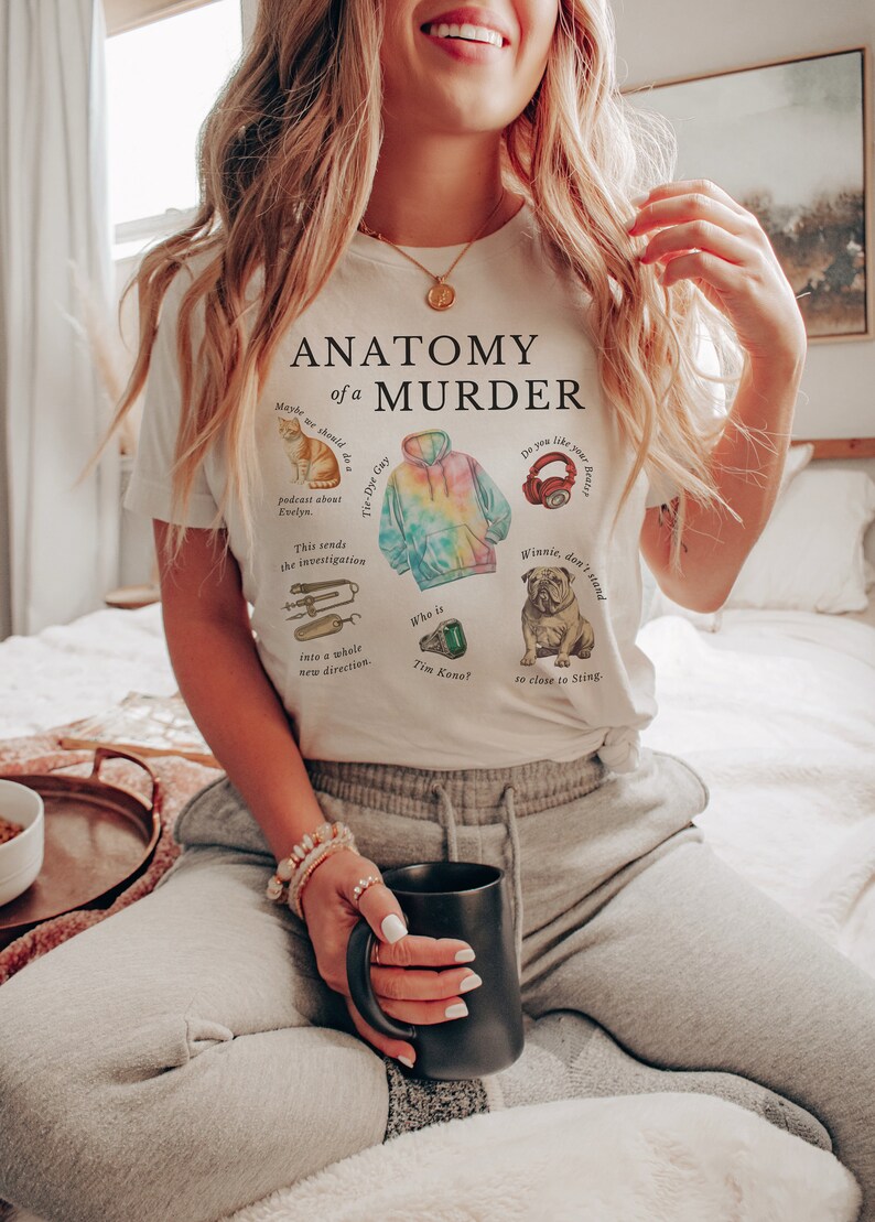 May include: White t-shirt with the text "Anatomy of a Murder" and illustrations of a cat, a tie-dye hoodie, headphones, a bulldog, and a wrench. The text on the shirt includes the phrases "Tie-Dye Gay", "podcast about Evelyn", "This sends the investigation into a whole new direction", "Who is Tim Kono?", and "Winnie, don't stand so close to Sting."
