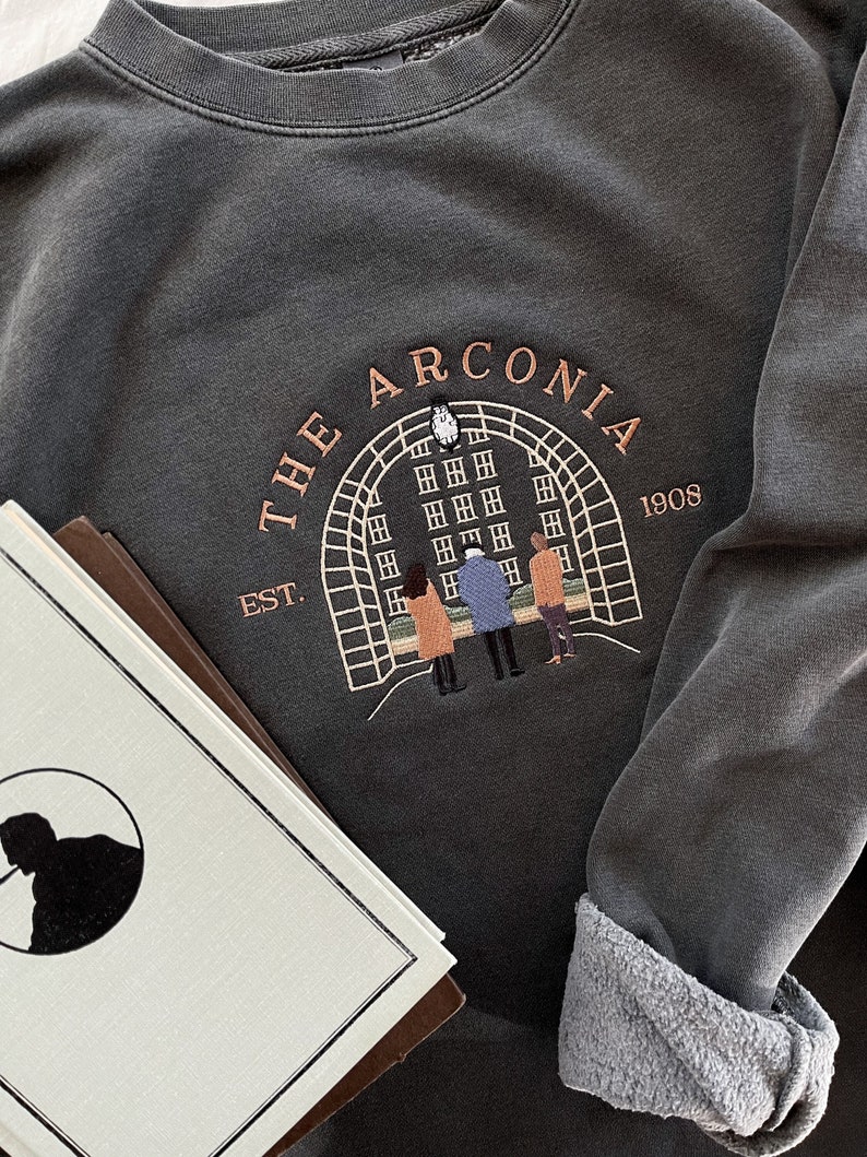 May include: A dark gray sweatshirt with an embroidered design featuring a building with the text "THE ARCONIA EST. 1908".