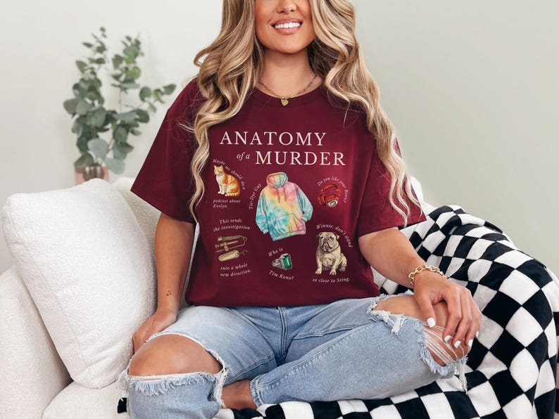 May include: A maroon t-shirt with the text "Anatomy of a Murder" and illustrations of a cat, a tie-dye hoodie, a ring, a metal object, a green gem, and a dog.