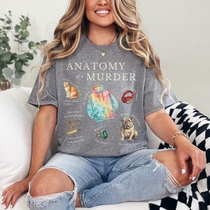 May include: A gray t-shirt with the text "Anatomy of a Murder" and illustrations of a cat, a tie-dye hoodie, headphones, a ring, and a dog.