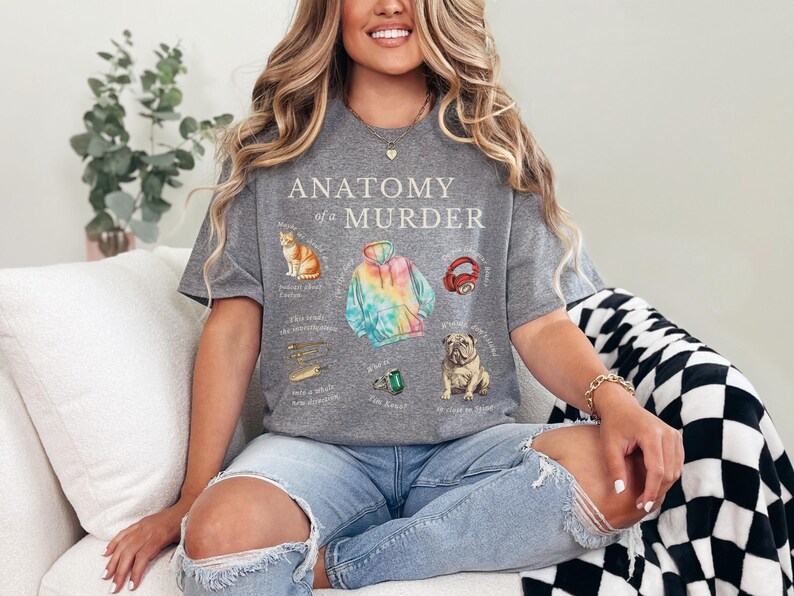 May include: A gray t-shirt with the text "Anatomy of a Murder" and illustrations of a cat, a tie-dye hoodie, headphones, a ring, and a dog.