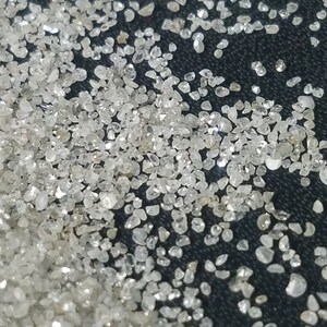 Puede incluir: Primer plano de una dispersi&oacute;n de peque&ntilde;as piedras preciosas claras y brillantes. Las piedras preciosas tienen forma irregular y reflejan la luz, creando un efecto brillante. El fondo es una superficie oscura y texturizada.