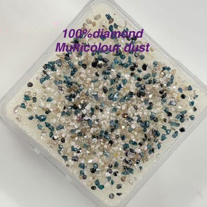 May include: A clear plastic container filled with multicolored diamond dust. The dust includes shades of blue, black, and tan. Text on the container reads "100% diamond Multicolour dust."