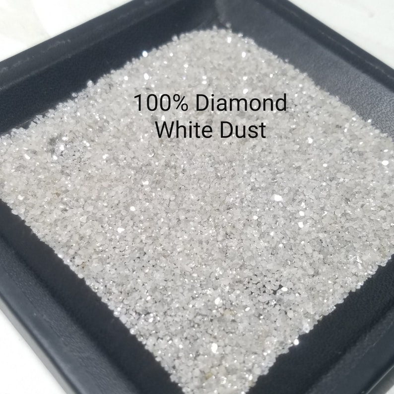 Puede incluir: Primer plano de una bandeja negra llena de polvo de diamante blanco. El texto "100% Diamond White Dust" est&aacute; impreso en negro. El polvo de diamante brilla, reflejando la luz.