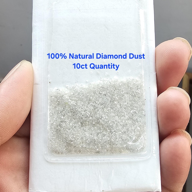 Puede incluir: Un peque&ntilde;o paquete de pl&aacute;stico transparente que contiene polvo de diamante. El texto en el paquete dice "100% Natural Diamond Dust 10ct Quantity". El polvo de diamante aparece como una sustancia fina y granular.