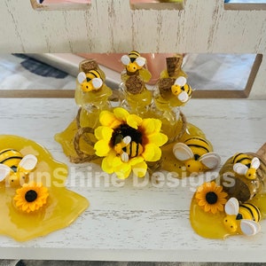May include: A honey themed craft with a sunflower, bees, and honey jars. The honey is dripping from the jars and a honey dipper is in the scene.