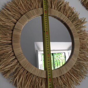 May include: A round mirror with a natural woven straw frame. The frame has a fringe of straw around the edge. The mirror is 40 inches in diameter.