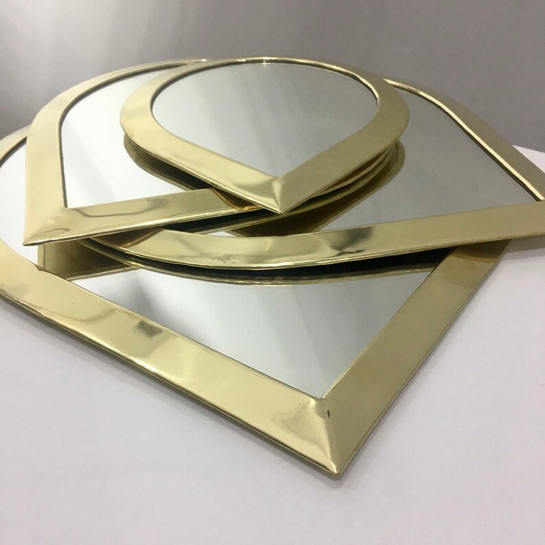 May include: Three gold-toned, teardrop-shaped mirrors with beveled edges are stacked on top of each other.
