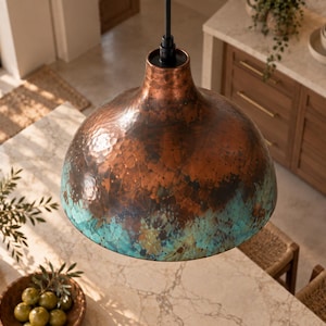 May include: A dome-shaped pendant light fixture featuring a hammered copper finish on the upper portion that transitions into a vibrant turquoise patina at the lower edge, suspended from a black cord and a simple black cylindrical socket mount.