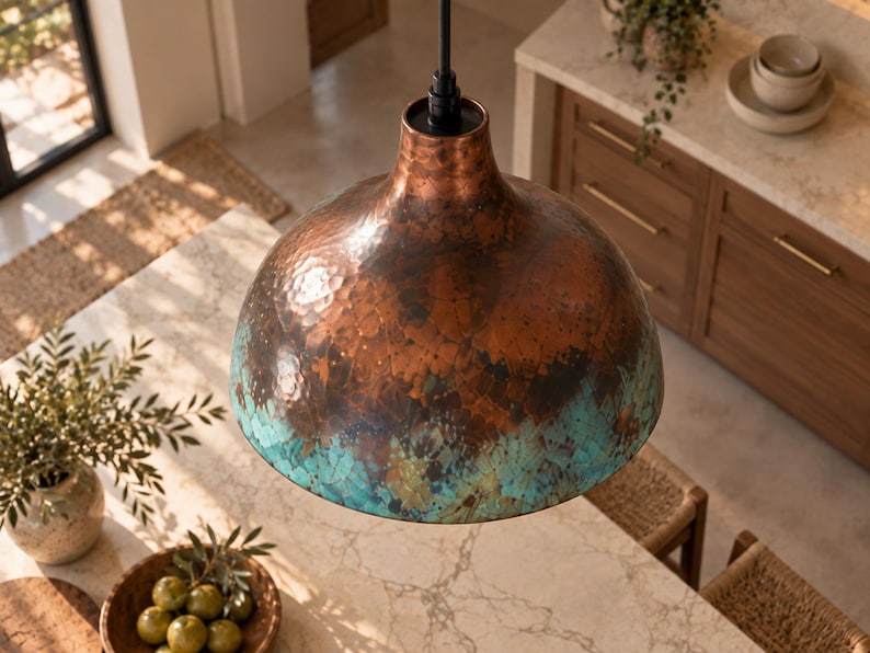 May include: A dome-shaped pendant light fixture featuring a hammered copper finish on the upper portion that transitions into a vibrant turquoise patina at the lower edge, suspended from a black cord and a simple black cylindrical socket mount.