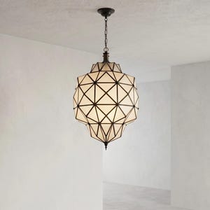 May include: A geometric pendant light fixture featuring a dark metal frame with a complex, multi-faceted structure. The frame holds opaque white panels in a triangular pattern, suspended from the ceiling by a matching dark metal chain and canopy.