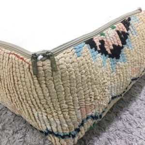 May include: A beige, cream, and blue patterned floor cushion with a zipper closure. The cushion has a white fabric lining and two bronze zipper pulls.