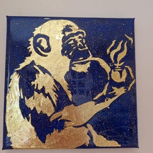 Puede incluir: Una silueta dorada de un mono sosteniendo una taza de café humeante sobre un fondo azul oscuro.