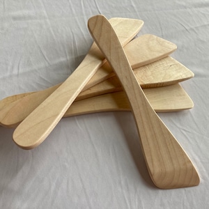 May include: Set of five wooden spatulas, all natural wood color, arranged in a fan shape.