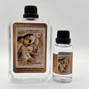 Peut inclure: Deux flacons en verre transparent avec bouchons noirs contenant de l'après-rasage. Le grand flacon rectangulaire est étiqueté French Pot 100ml, et le petit flacon cylindrique présente une illustration vintage assortie de personnes et de texte.