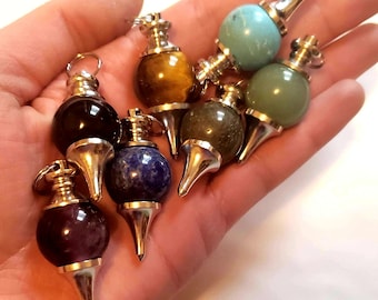 May include: Seven crystal pendulums with silver tips, each with a different color stone: amethyst, lapis lazuli, green aventurine, tiger's eye, black obsidian, turquoise, and green aventurine.