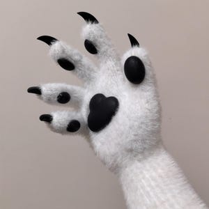 May include: A white furry hand with black paw pads and claws. The hand is raised with fingers spread apart.