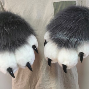 Puede incluir: Un par de marionetas de mano de garra peludas grises y blancas con garras negras.