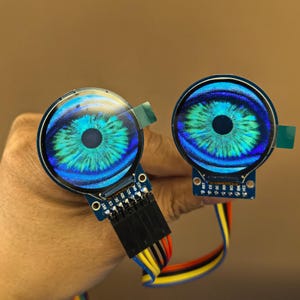 Könnte beinhalten: Zwei runde, blau-grüne Displays in Augenform mit einer blauen Platine und schwarzen Drähten.