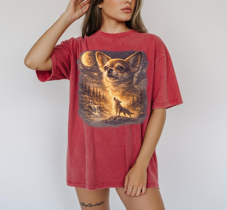 May include: Red t-shirt featuring a detailed graphic of a Chihuahua with a full moon and a howling wolf in a forest setting. The shirt has short sleeves and a relaxed fit.