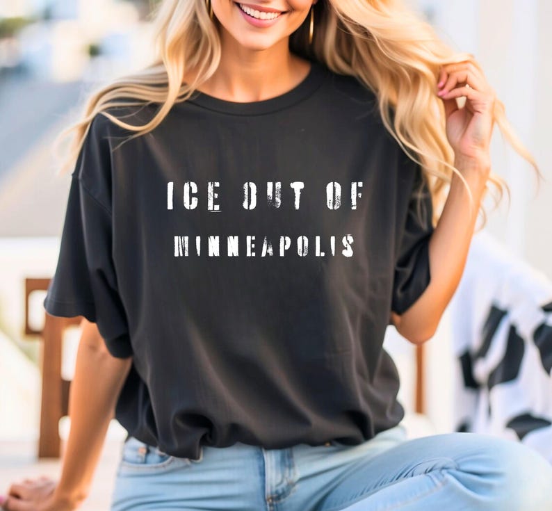 Puede incluir: Camiseta negra con el texto blanco "ICE OUT OF MINNEAPOLIS" en letras desgastadas. La camiseta es de color oscuro y parece estar hecha de un material suave. La camiseta es de estilo casual.