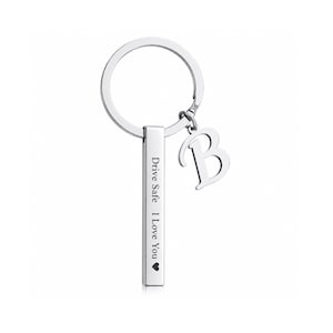 May include: A silver-toned metal keychain featuring a circular ring, a vertical rectangular bar pendant engraved with the text Drive Safe I Love You and a heart symbol, and a separate dangling charm in the shape of the capital letter B.