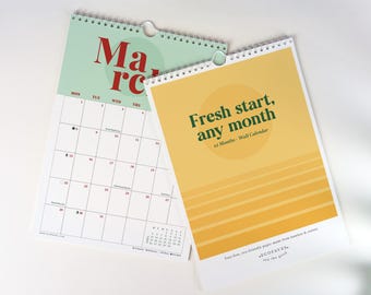 May include: Two spiral-bound wall calendars. One calendar shows a light green page with the red text March and a grid of dates. The other calendar has a yellow cover with the dark green text Fresh start, any month and 12 Months - Wall Calendar.
