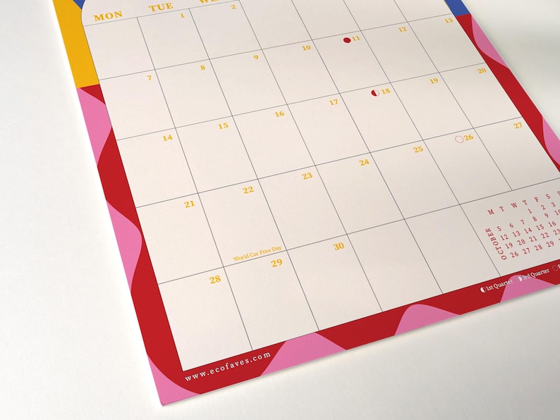 May include: A monthly calendar with a cream-colored background and a grid layout. The days of the week are across the top in yellow. The calendar has a red, pink, yellow, and blue border. The website www.ecofaves.com is at the bottom.