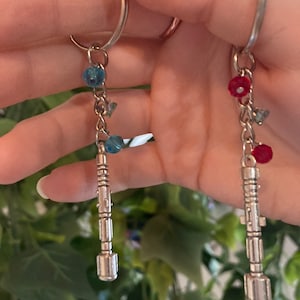 Pu&ograve; includere: Due portachiavi argentati con perline di cristallo blu e rosse e un ciondolo argentato a forma di cacciavite sonico.