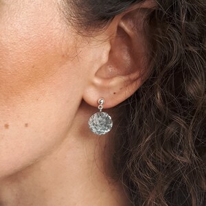 May include: Silver hammered disc earrings with a small silver bead at the top.