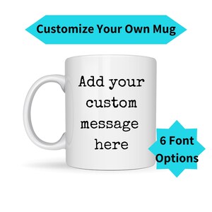 Puede incluir: Taza de cerámica blanca con asa negra. La taza tiene el texto "Add your custom message here" impreso en ella. Hay una forma de estrella azul con el texto "6 Font Options" impreso en ella.