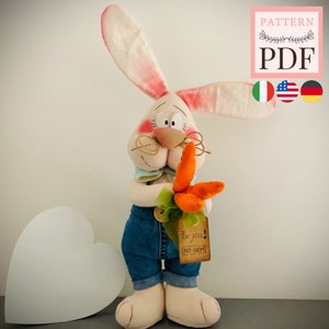 May include: A plush bunny toy wearing blue overalls and holding a bunch of orange carrots. The bunny has a white face with pink cheeks and brown eyes. The bunny is holding a tag that says "For you! No OGM!"