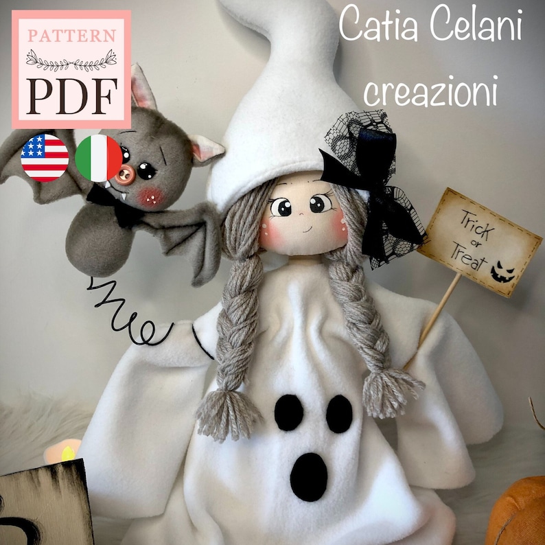K&ouml;nnte beinhalten: Eine wei&szlig;e Geisterpuppe mit grauen Z&ouml;pfen, die ein wei&szlig;es Geisterkost&uuml;m mit schwarzen Augen und einem Mund tr&auml;gt. Die Puppe h&auml;lt ein Schild mit der Aufschrift "Trick or Treat" und hat eine Fledermaus mit roten Augen und einer rosa Nase daneben.