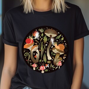 May include: Black t-shirt with a circular design featuring mushrooms, snails, and leaves in shades of brown, green, red, and white.