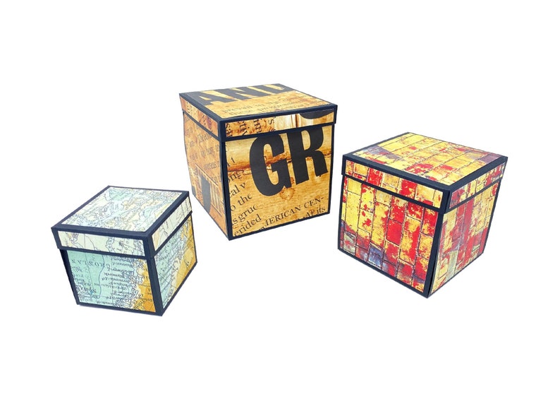 May include: Three decorative boxes with different patterns. The largest box is brown with black text that says "GR". The medium box is yellow, red, and orange with a brick pattern. The smallest box is blue and green with a map pattern.