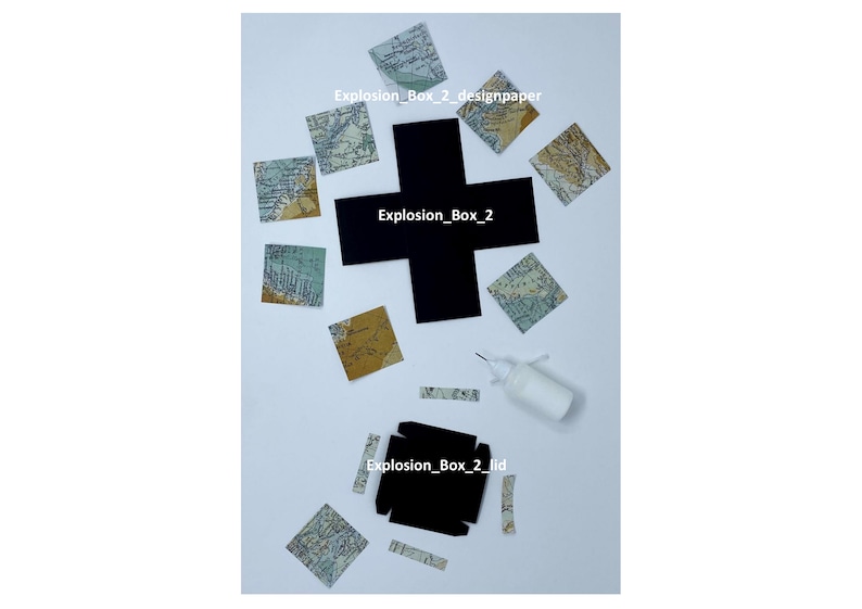 May include: A black paper explosion box with the text "Explosion_Box_2" on the front. The box is surrounded by small squares of patterned paper with a map design. A bottle of glue and a few strips of paper are also visible.