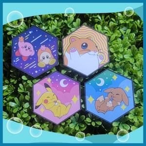May include: Four hexagonal stickers featuring cartoon characters. One shows Kirby and a friend in a purple and blue space scene. Another depicts a hamster with a yellow and white background. Pikachu and Eevee are also featured.