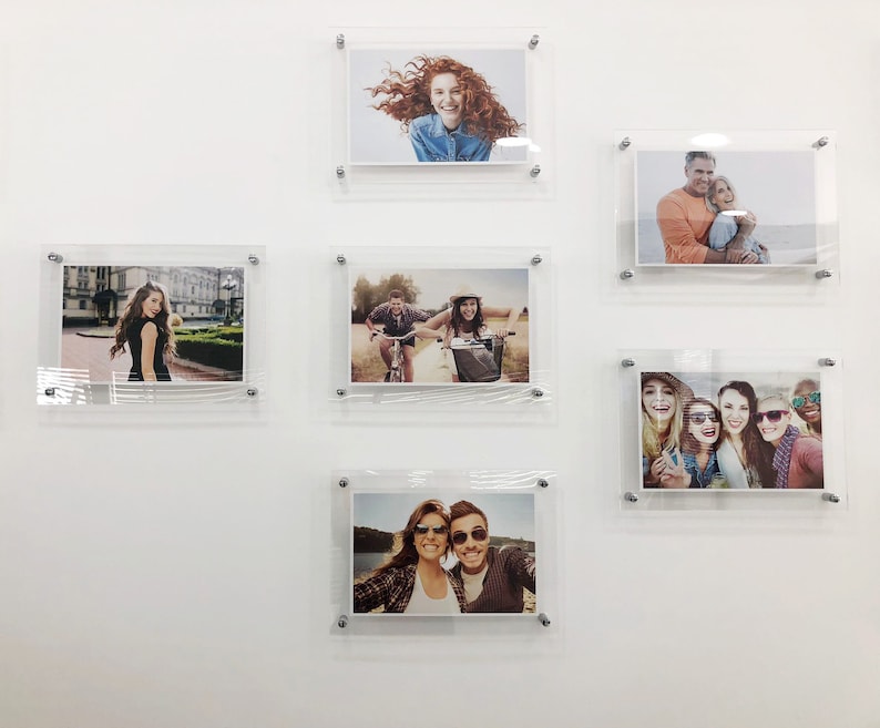 May include: A white wall with six framed photographs. The photographs are of different people and places. The photographs are all in black and white.