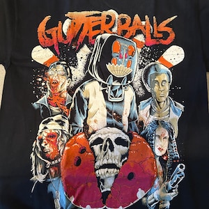 Puede incluir: Camiseta negra con un estampado gráfico de una banda llamada "Gutterballs". El gráfico presenta una calavera, bolos y varios personajes con caras ensangrentadas.