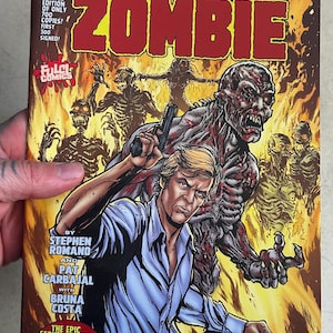 May include: Comic book cover featuring a man holding a gun, facing a zombie with a red, bloody, and skeletal appearance. The cover is titled "Lucio Fulci's Zombie: War of the Dead!" and features a fiery background.