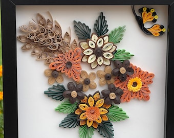 Könnte beinhalten: Ein gerahmtes Papierbastelwerk mit einem Strauß aus orangefarbenen, gelben, braunen und grünen Papierblumen mit einem Schmetterling in der oberen rechten Ecke.