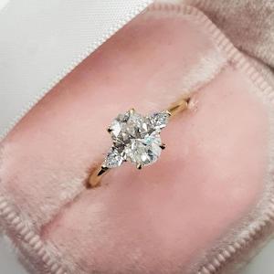 Oval förlovningsring med tre stenar i moissanit och päronstenar på sidan