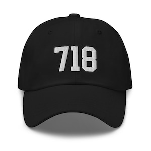 May include: A black baseball cap with white embroidered text that reads "718".